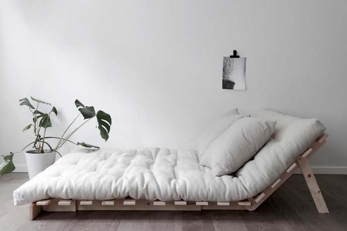 Minimalistyczna sypialnia z futonem na drewnianym stelażu w roli głównej