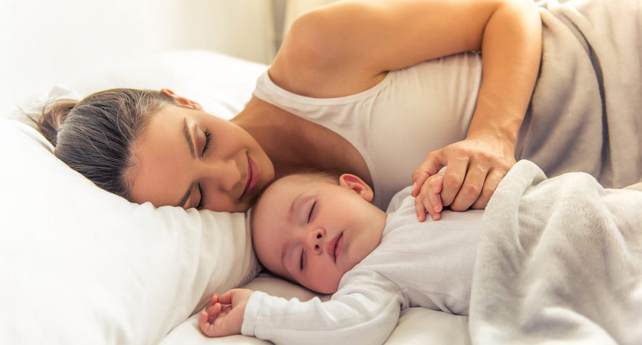 Młoda kobieta śpiąca w łóżku z niemowlęciem - zdrowy-sen.eu