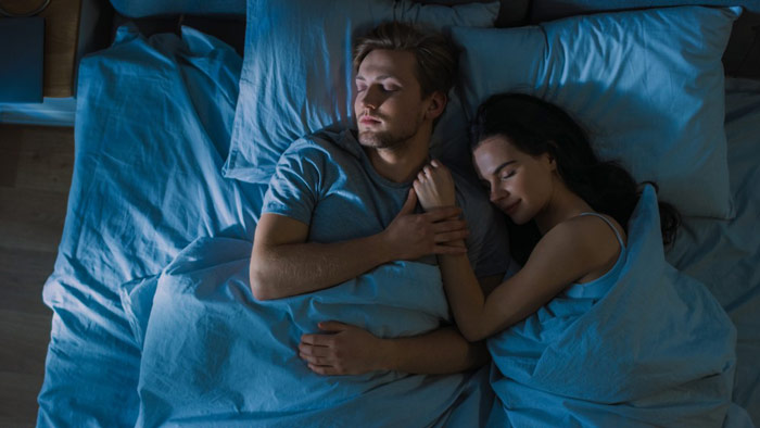 Mężczyzna i kobieta, po uspokojeniu nerwów przed snem, smacznie śpią przytuleni do siebie w swojej sypialni - zdrowy-sen.eu