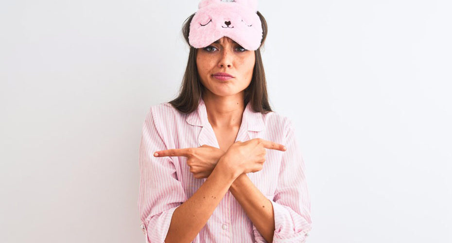 Kobieta w różowej piżamie zastanawiająca się nad prawidłowym kierunkiem spania - zdrowy-sen.eu