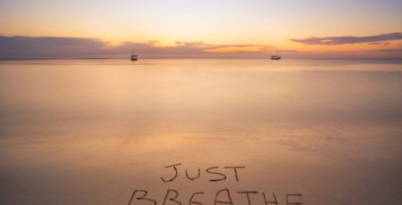 Napis na piasku nad morzem „Just breathe” nawiązujący do relaksacyjnej metody 4-7-8 – zdrowy-sen.eu