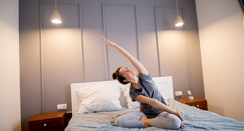Kobieta praktykuje jogę w łóżku przed zaśnięciem – zdrowy-sen.eu