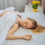 Młoda kobieta śpiąca na plecach bez poduszki w białej pościeli – zdrowy-sen.eu