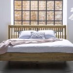 Duże łóżko drewniane na tle okna i ceglanej ściany – zdrowy-sen.eu