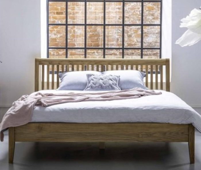 Duże łóżko drewniane na tle okna i ceglanej ściany – zdrowy-sen.eu