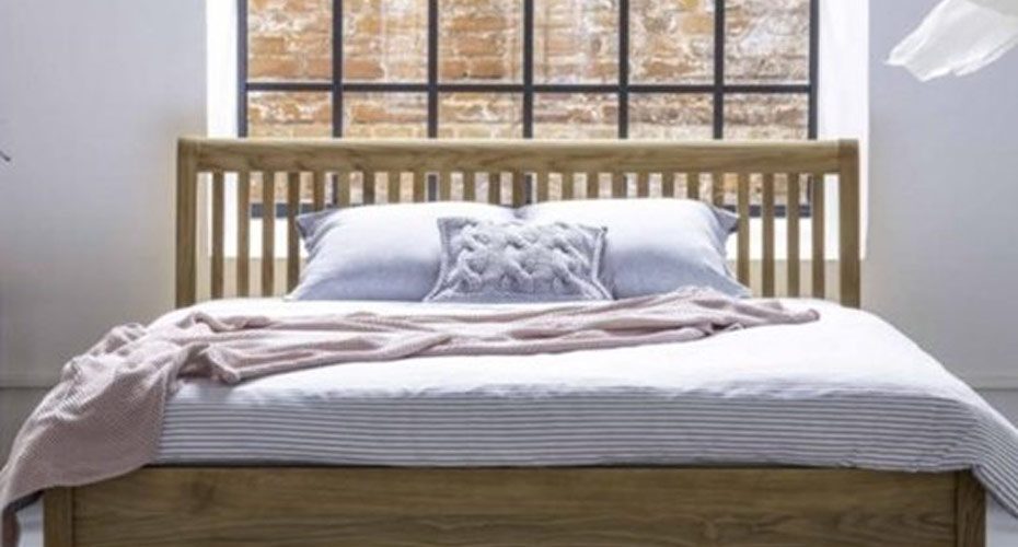 Duże łóżko drewniane na tle okna i ceglanej ściany – zdrowy-sen.eu